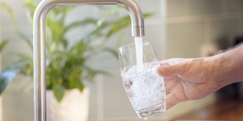 Filling up a glass with clean drinking water from kitchen faucet